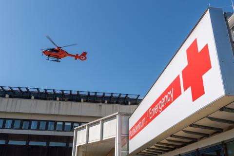 roter Rettungshubschrauber startet vom Dach des Klinikums
